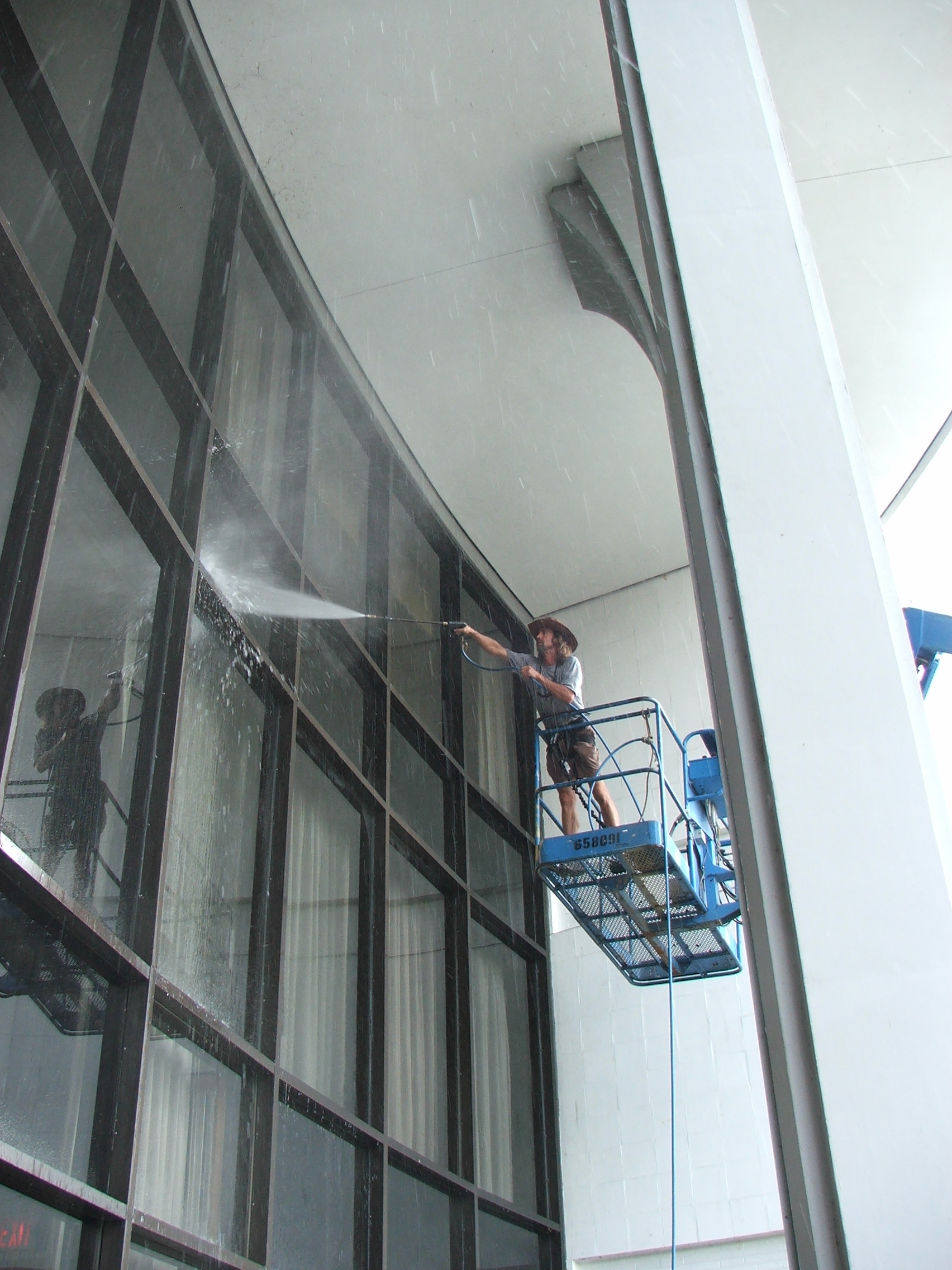Pressure washing glass front entrance to remove dirt, cob webs and debris